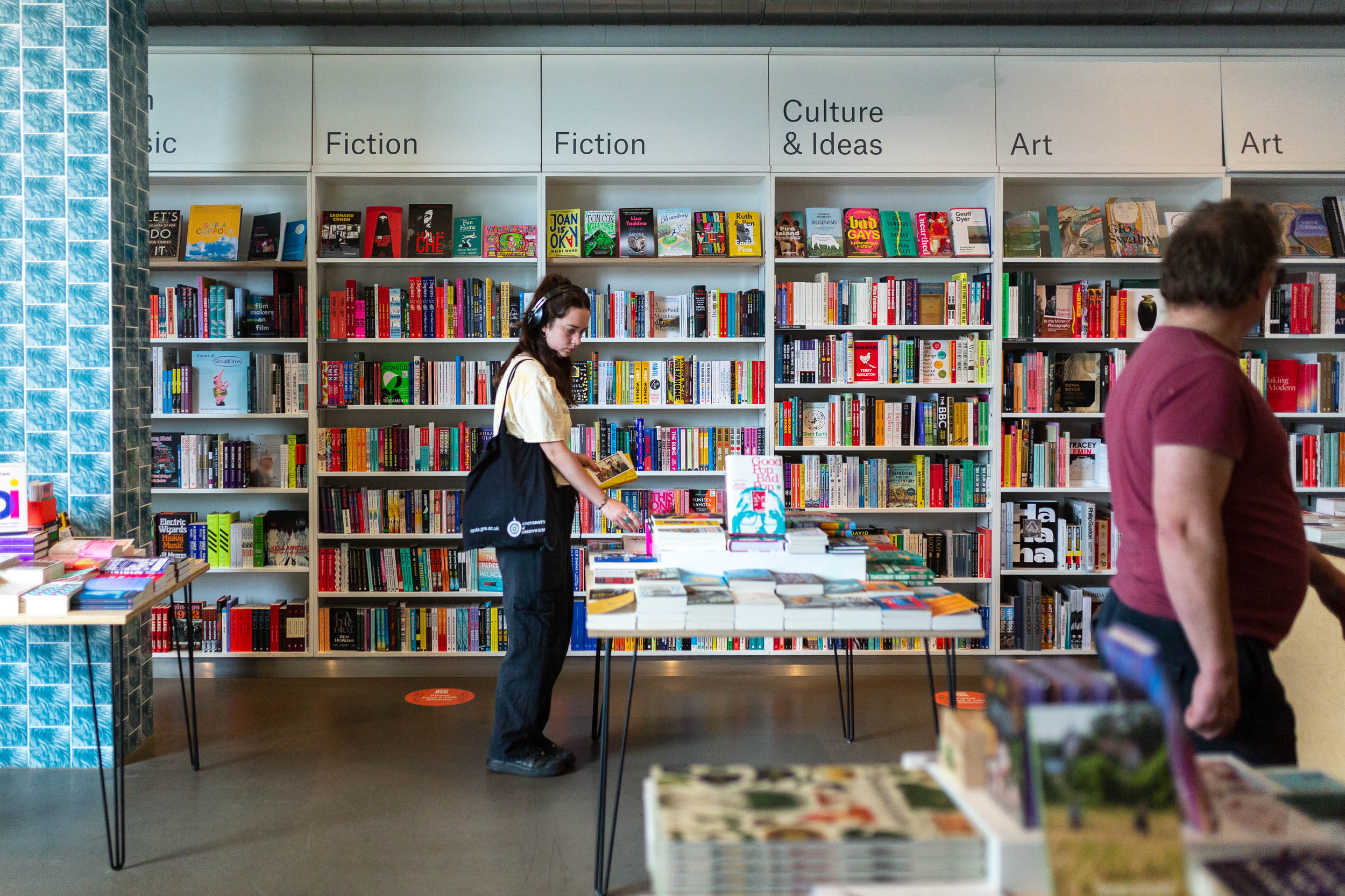 A coloured photograph of a person standing at the bookshop table, looking at a book.