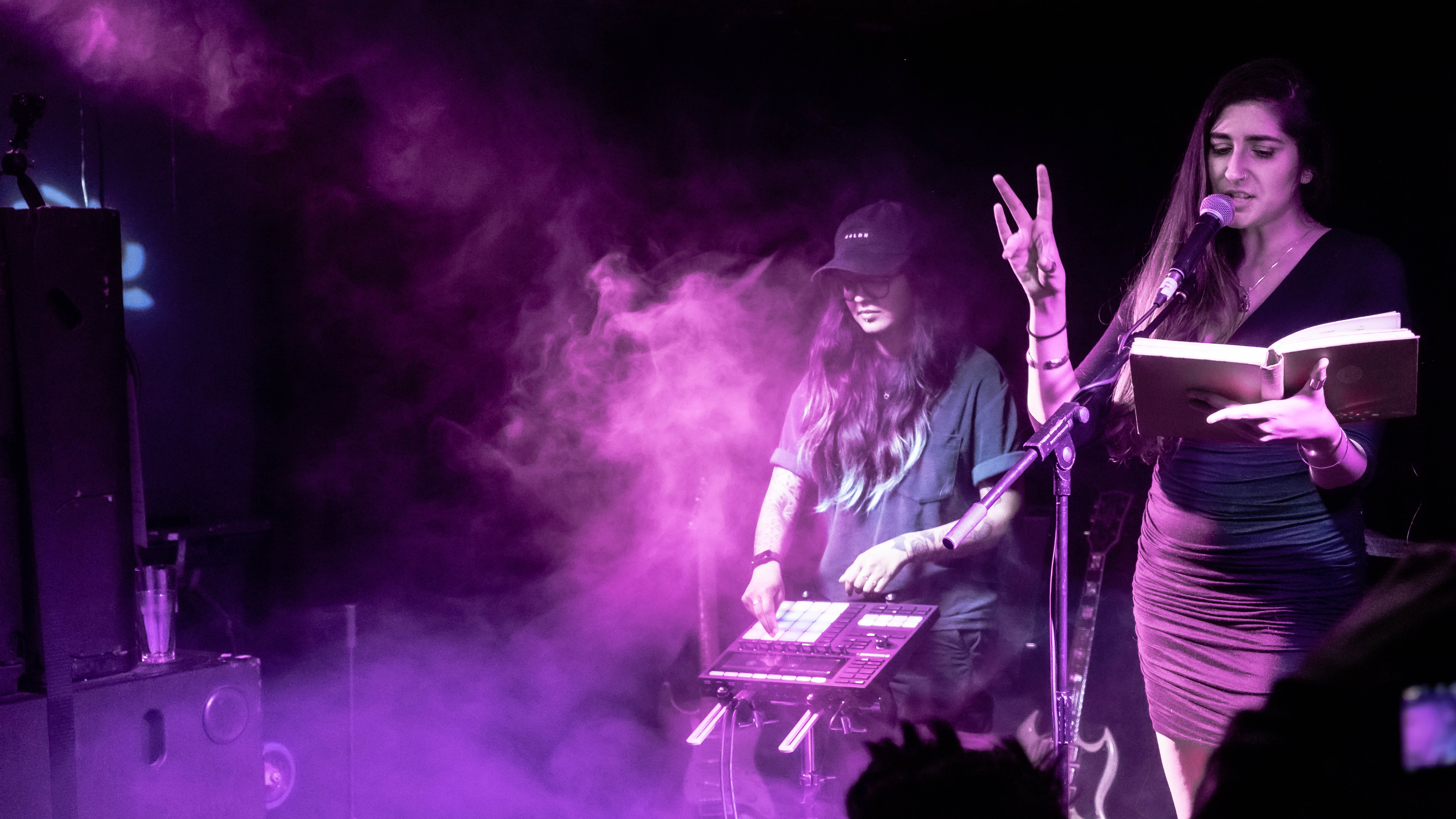 A colour photograph of performers Gnarly and Nikita on a purple lit stage.