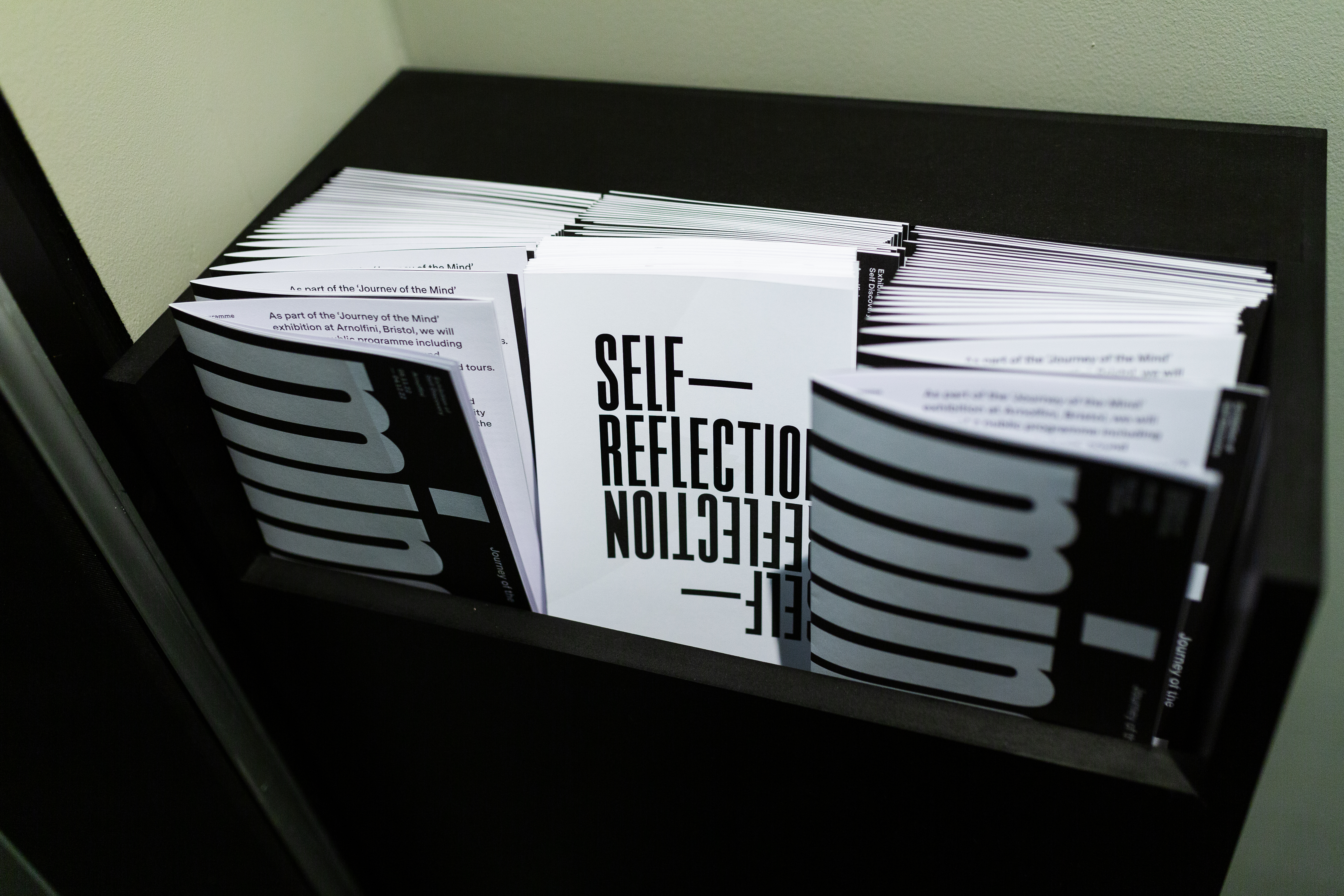 A photograph of a a display case full of Journey of the Mind and Self Reflection booklets.