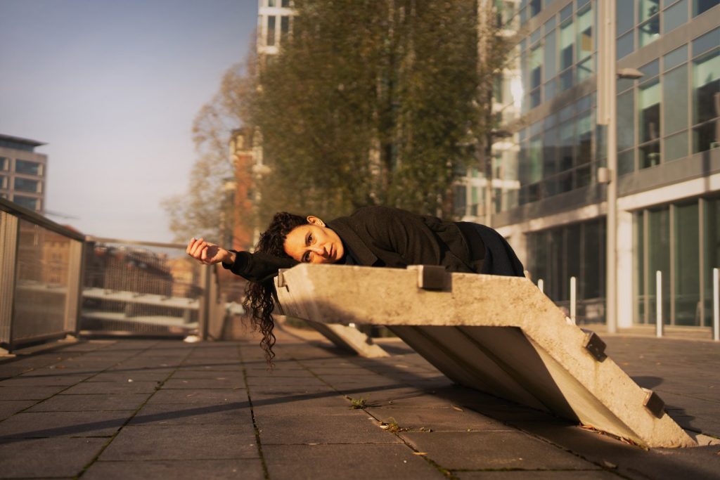 A colour photograph of Raquel Meseguer Zafe lying on her side on a concrete block, facing the photographer.