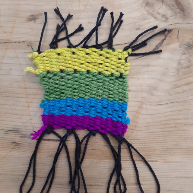 Weaved yarn in black, yellow, green, blue and purple.