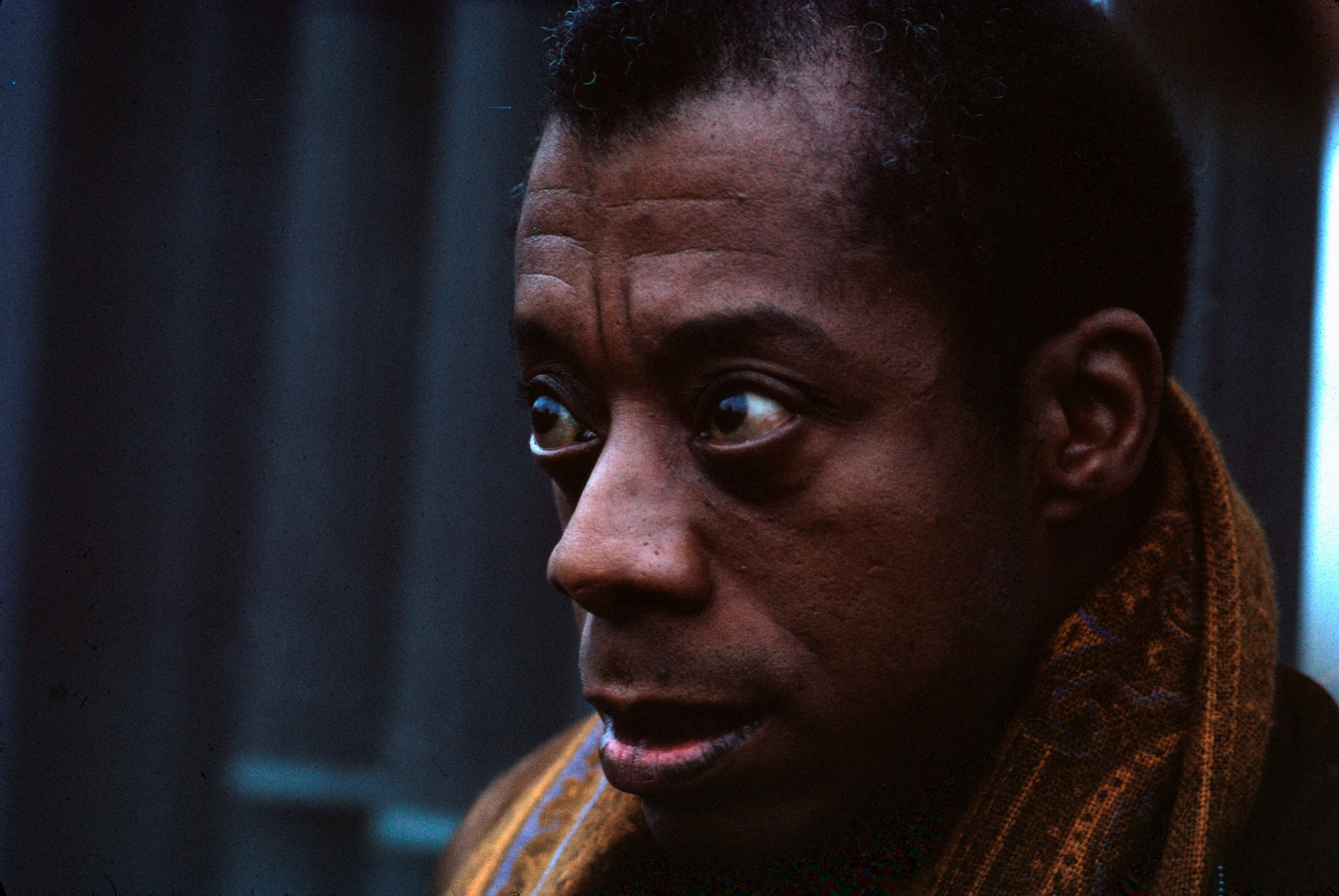 A close up colour photograph of writer James Baldwin