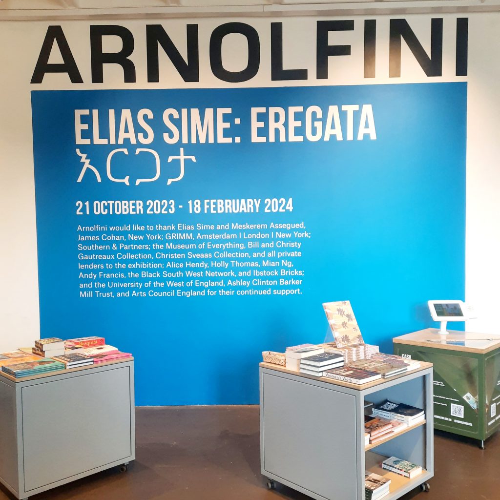 a colour photograph a blue coloured wall over which are laid white vinyl lettering installed by Nick Billington for an exhibition at Arnolfini.