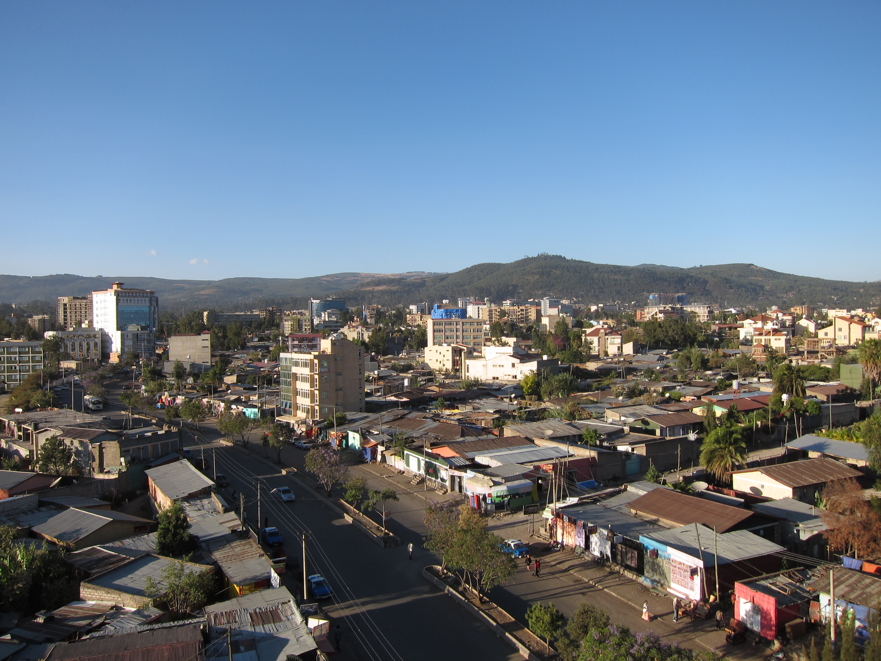 View over Addis Ababa city, showing buildings and roads, with the mountains in the background.